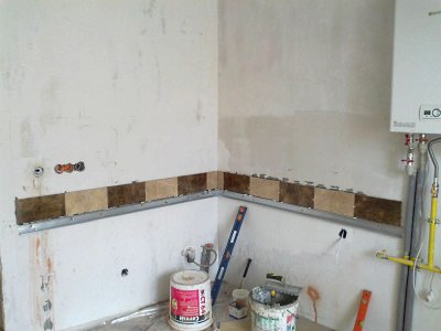 Укладка нижнего маячного ряда на стене в кухне